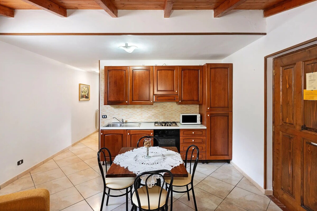 A kitchen with wooden cabinets, a dining table with chairs, a microwave, and a stove.