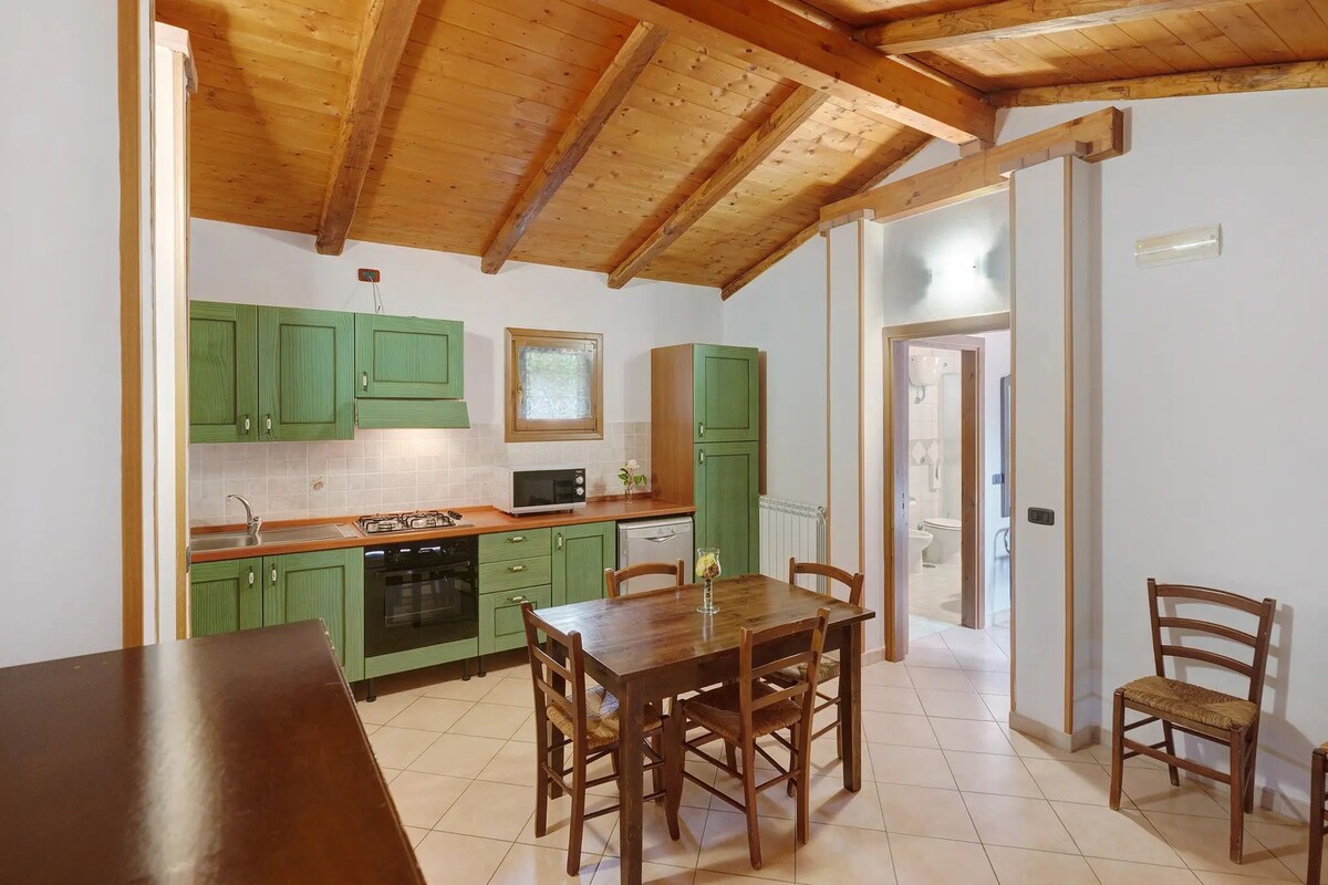 A kitchen with green cabinets, a wooden table, and chairs.