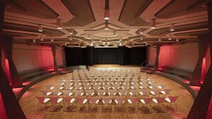 A theater with a circular stage and rows of chairs arranged in a semi-circular pattern.