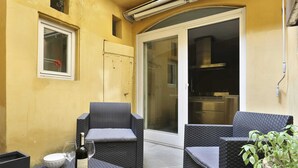 A small outdoor seating area with wicker furniture, a bottle of wine, and a glass on a table. - Short-let Florence Pontevecchio Suite (Florence)