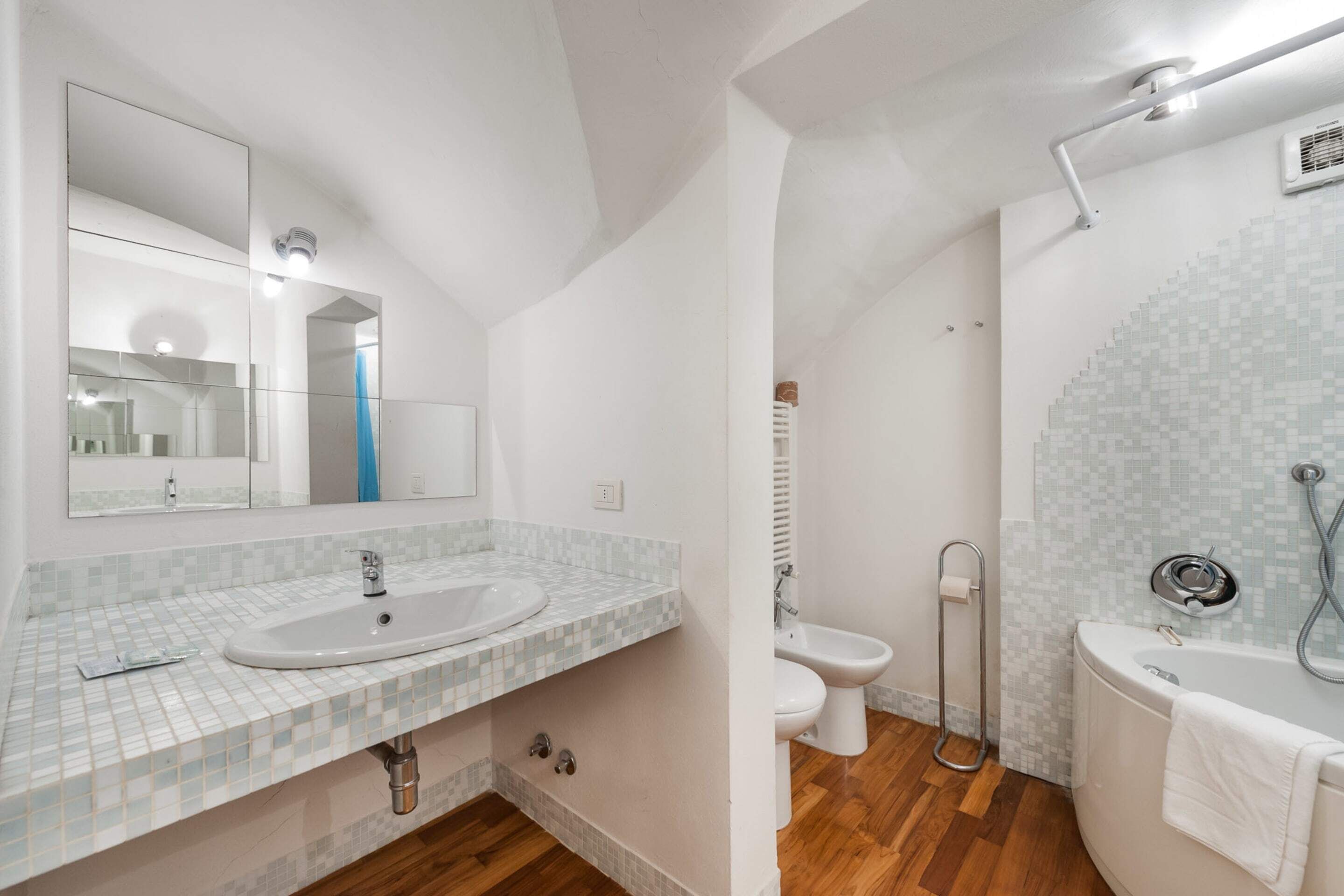 Un bany modern amb un mirall gran, un lavabo, un vàter i una banyera.