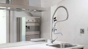 A modern kitchen with a stainless steel sink, a wall-mounted faucet, and a built-in oven. - Short-let Florence Pontevecchio Suite (Florence)