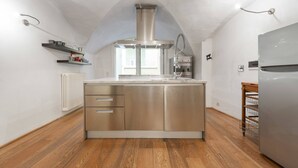 A modern kitchen with a central island, built-in appliances, and wooden flooring. - Short-let Florence Pontevecchio Suite (Florence)