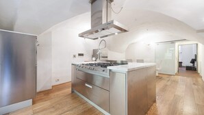 A modern kitchen with a stainless steel stove, a built-in oven, and a large island with a sink. - Short-let Florence Pontevecchio Suite (Florence)