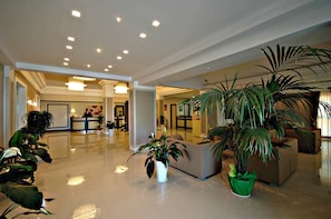 Eine geräumige Lobby mit Empfangsschalter, Sitzgelegenheiten und mehreren Zimmerpflanzen.