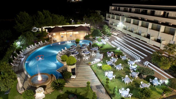 An aerial view of a hotel with a large swimming pool, outdoor seating areas, and a well-maintained garden. - Hotel Delle Canne (Amantea)