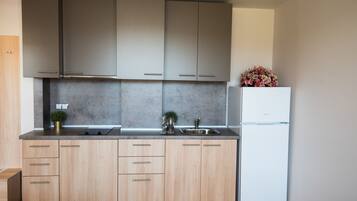 Una cocina moderna con armarios de madera clara, un lavamanos de acero inoxidable y un refrigerador blanco.