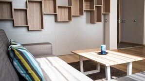 A modern living room with a sofa, a coffee table, and wooden shelves on the wall. - Court Inn (Panagyurishte)