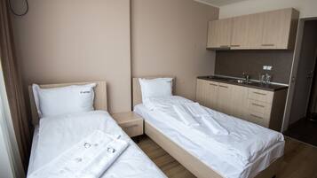 Una habitación de hotel con dos camas, kitchenette y baño.