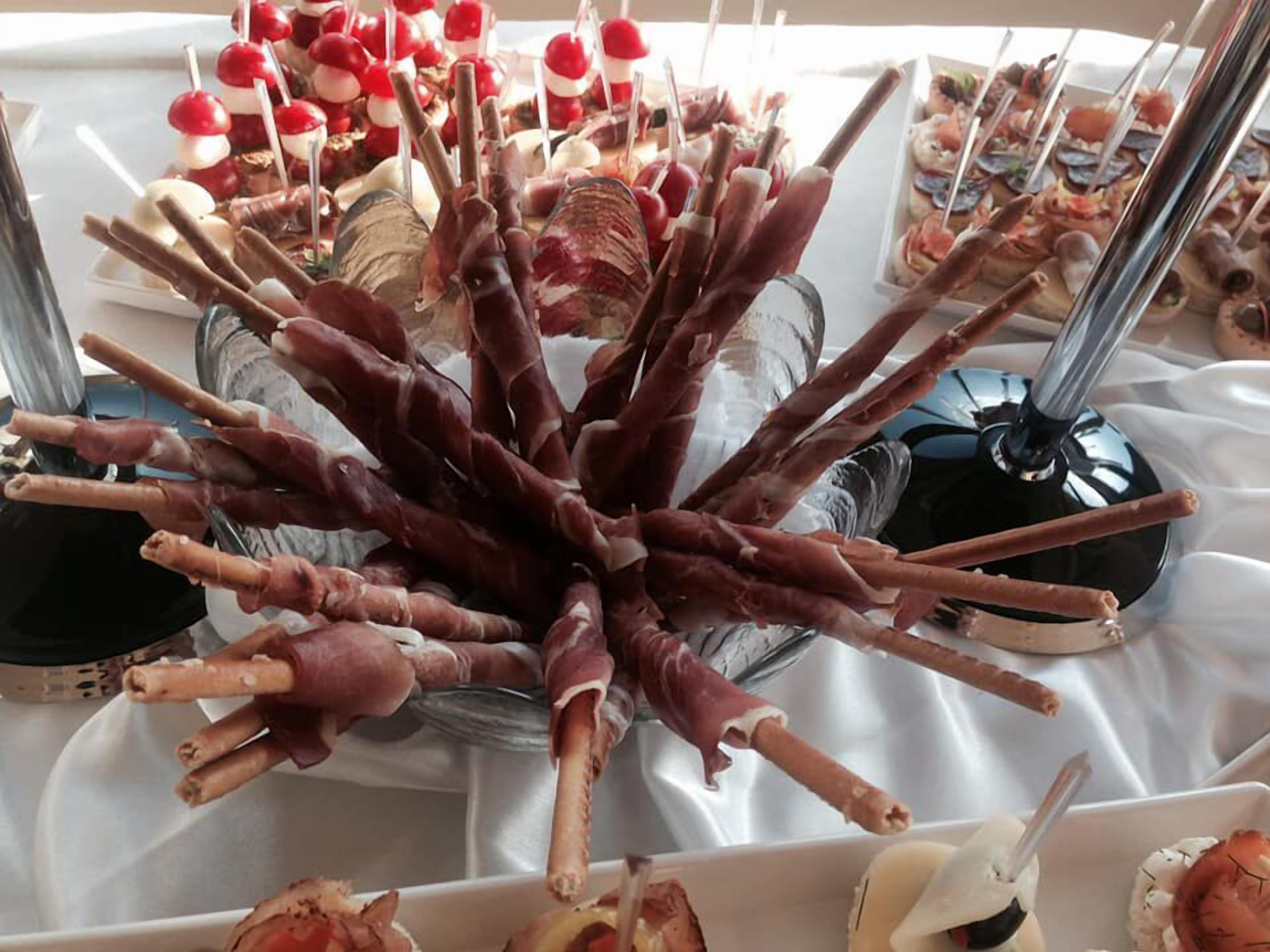 Una mesa de buffet con diversos alimentos, incluyendo brochetas de carne y verduras, y una variedad de otros platos.