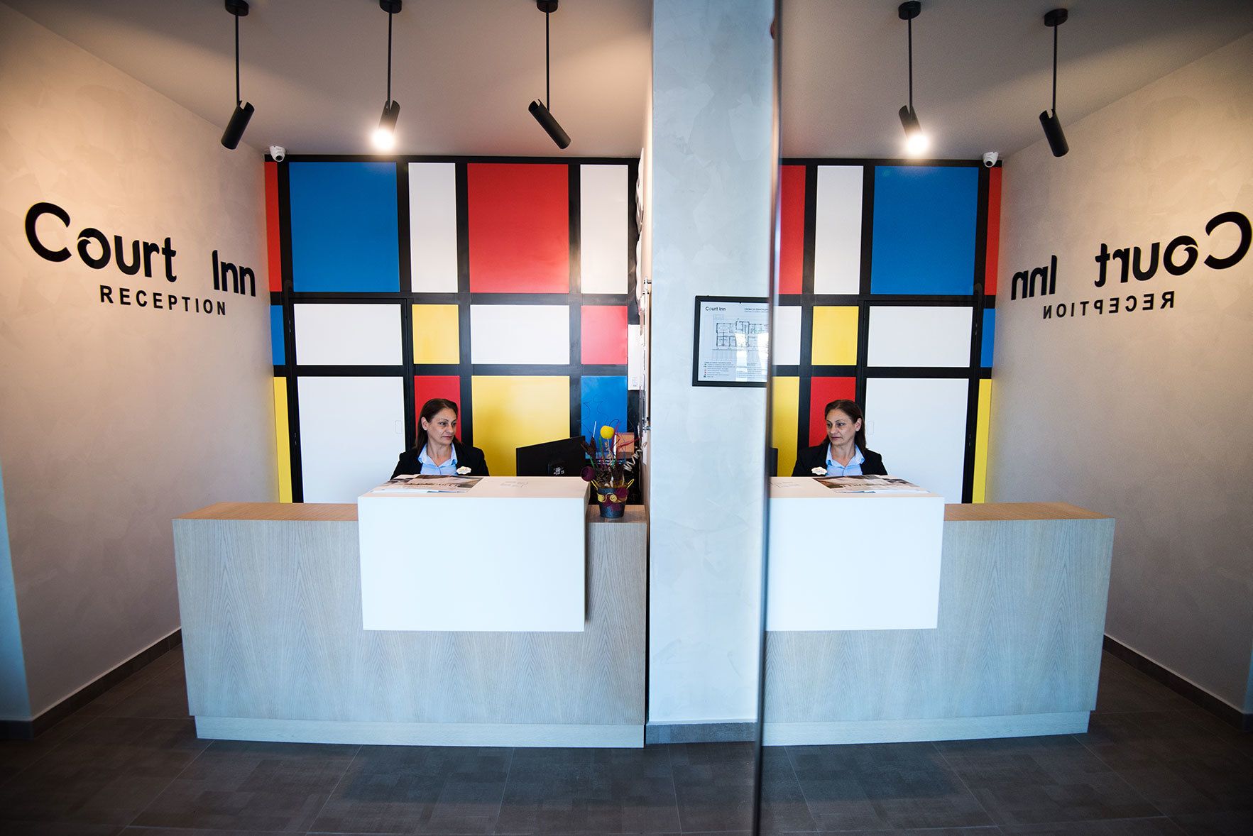 Tauleller de recepció a Court Inn amb disseny modern, que presenta una paret amb blocs de color i un certificat emmarcat a la paret darrere del tauleller.