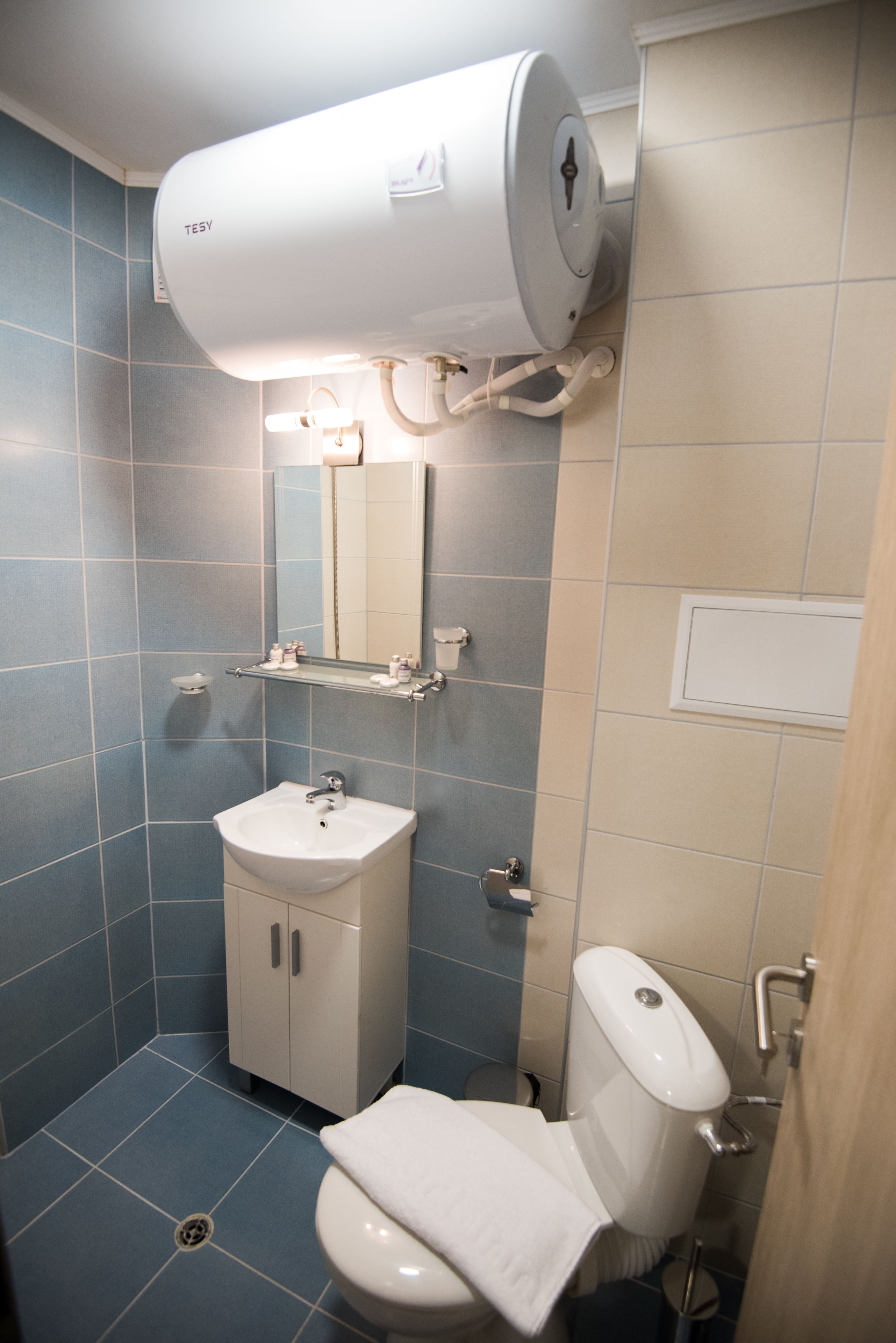 Baño con lavamanos, espejo y retrete blancos.