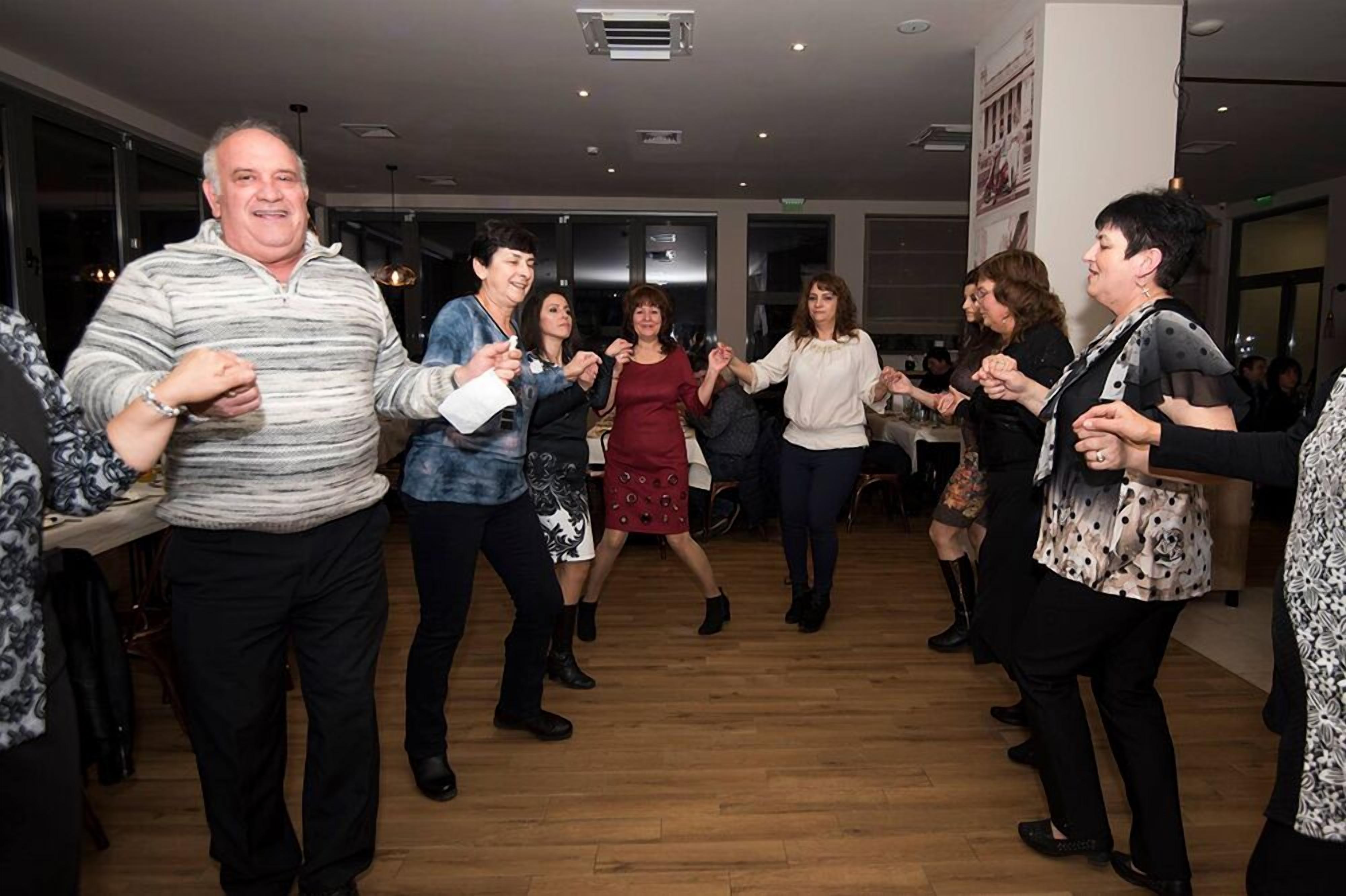 A group of people dancing in a spacious indoor area with wooden flooring and modern decor.