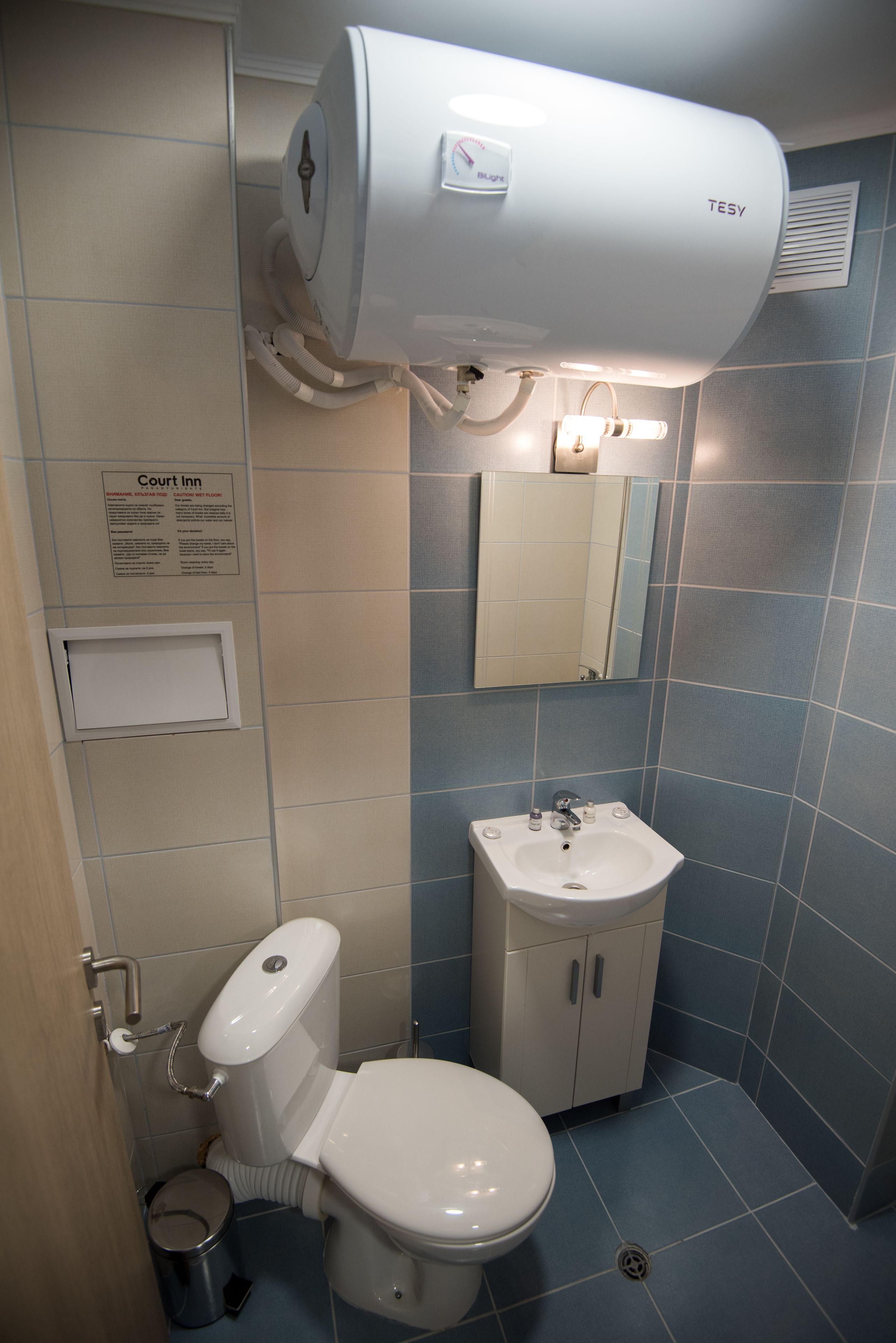 Een badkamer met toilet, wastafel en een wandgedroogde hand.'