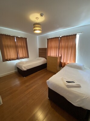 Habitación con 2 camas individuales, baño en la habitación | Espacio para trabajar con laptop y tabla de planchar con plancha