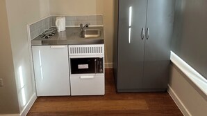 A compact kitchen with a built-in dishwasher, a sink, and a grey wardrobe. - Contractors Guest House (High Wycombe)