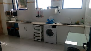 A compact kitchen with a washing machine, a microwave, and a sink.