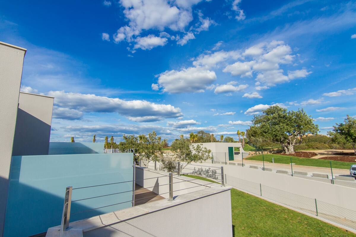 Un bâtiment moderne doté d’un toit plat, d’une allée pavée et d’un espace clos planté d’arbres.