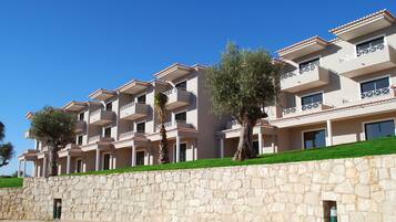 A multi-story hotel with balconies, stone walls, and green lawns.