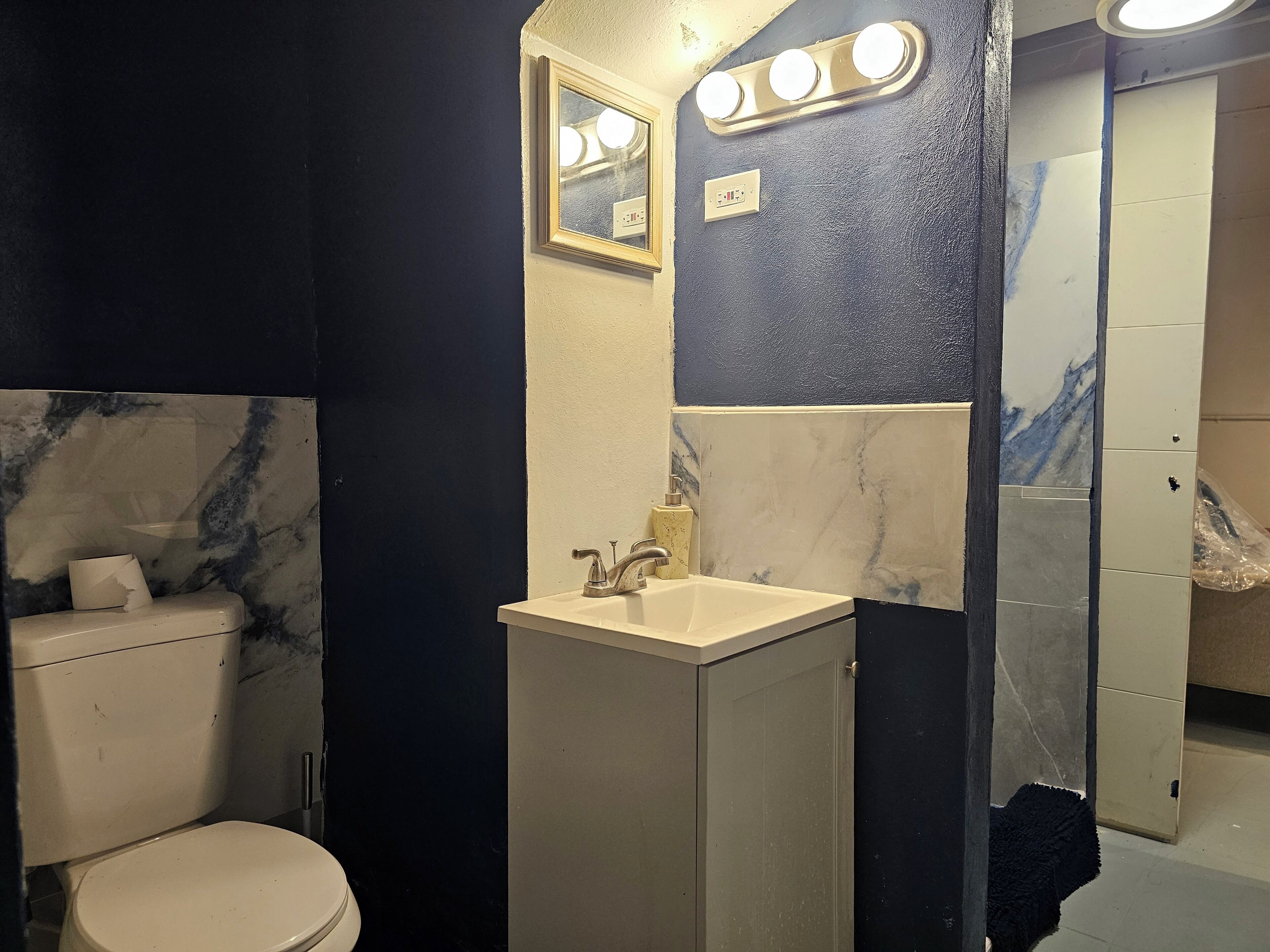 Een badkamer met toilet, wastafel en spiegel.