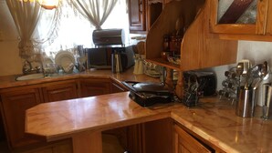 Una cocina con armarios de madera, una cafetera, un hervidor y diversos utensilios.