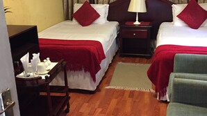Habitación de hotel con dos camas, un escritorio, una silla y una ventana con cortinas.