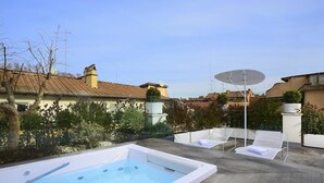 Ein Poolbereich auf dem Dach mit Whirlpool, Liegestühlen und einer Satellitenschüssel.