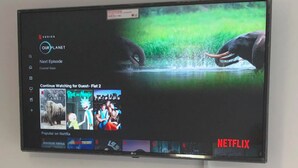A flat-screen TV mounted on a wall displaying a Netflix interface with 'Our Planet' and 'Continue Watching for Guest - Flat 2' options. - Two bedrooms self-contained flat with Free Parking - Flat 2 (Nottingham)