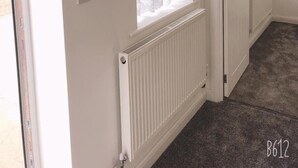 A room with a radiator, a clock, and a window with curtains. - Two bedrooms self-contained flat with Free Parking - Flat 2 (Nottingham)