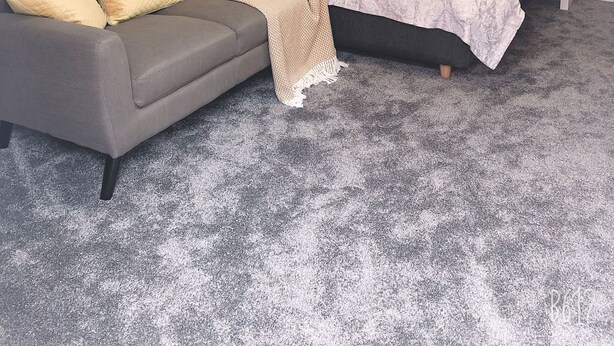 A bedroom with a grey sofa, a bed with patterned bedding, and a white bedside table. - Two bedrooms self-contained flat with Free Parking - Flat 2 (Nottingham)