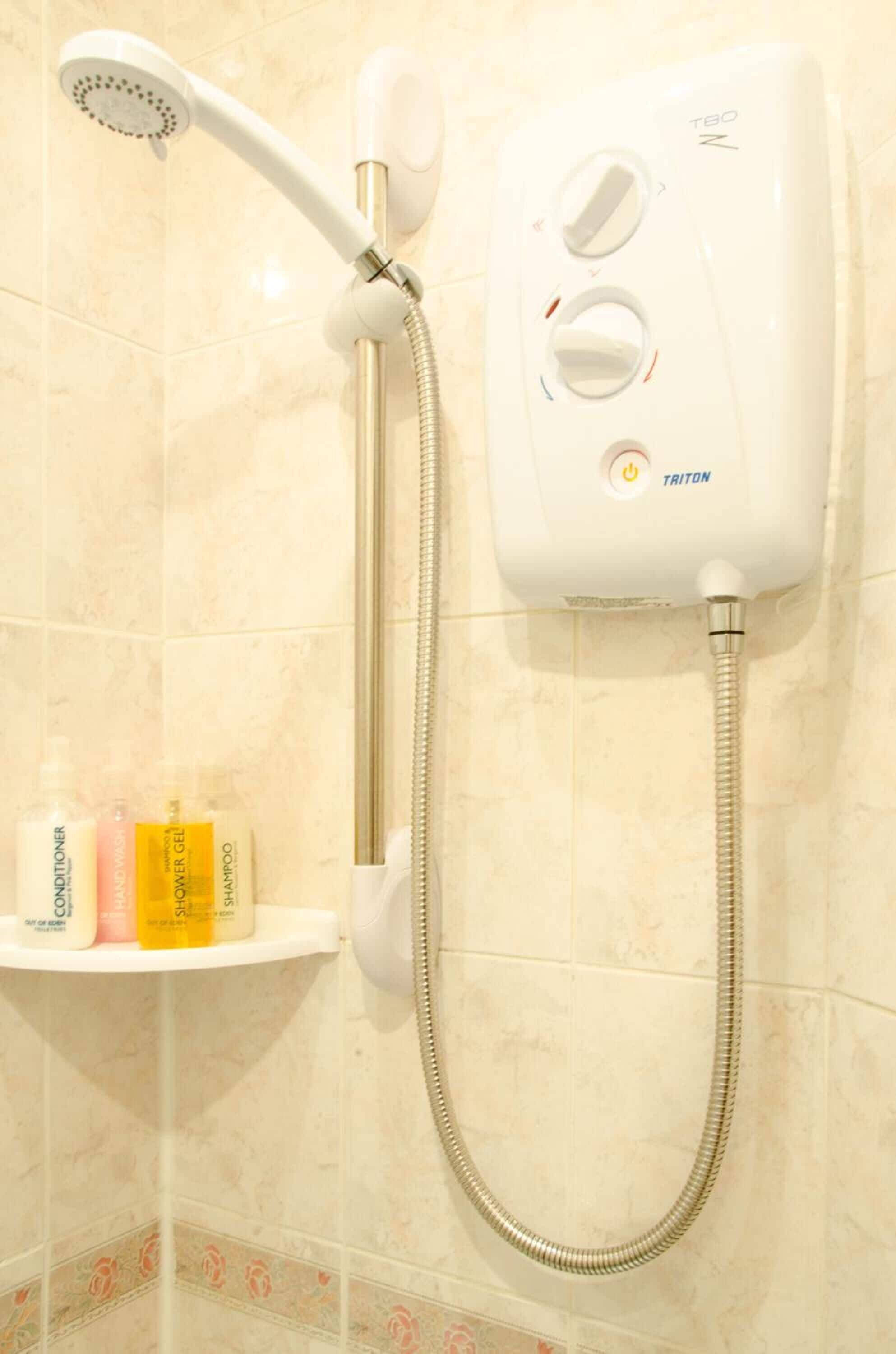 A wall-mounted shower with a handheld showerhead and control knobs.