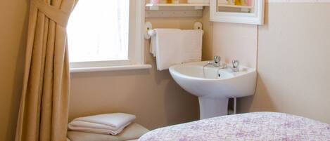 A bathroom with a sink, mirror, and toiletries.