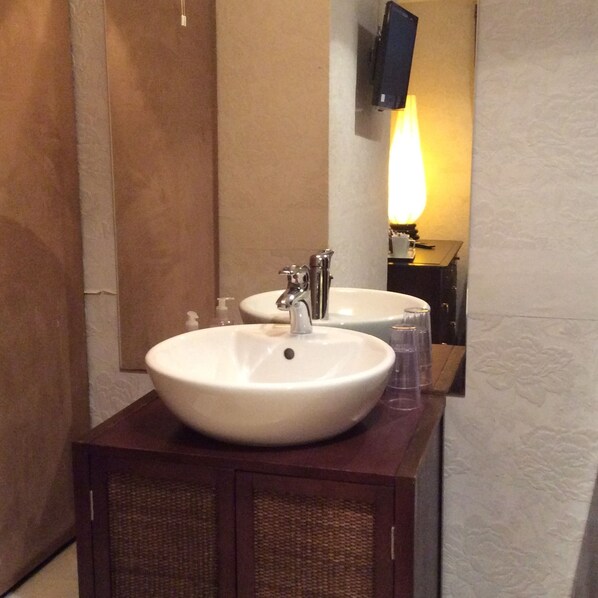 A bathroom with two sinks, a mirror, and a wall-mounted TV.