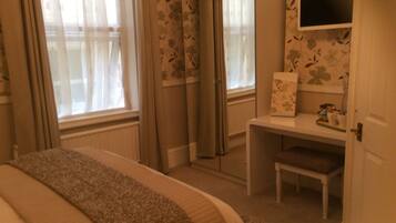 A bedroom with a bed, a desk, a chair, and a television.
