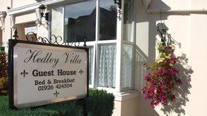 Schild für Hedley Villa Guest House mit Werbung für Bett und Frühstück sowie Kontaktnummern.
