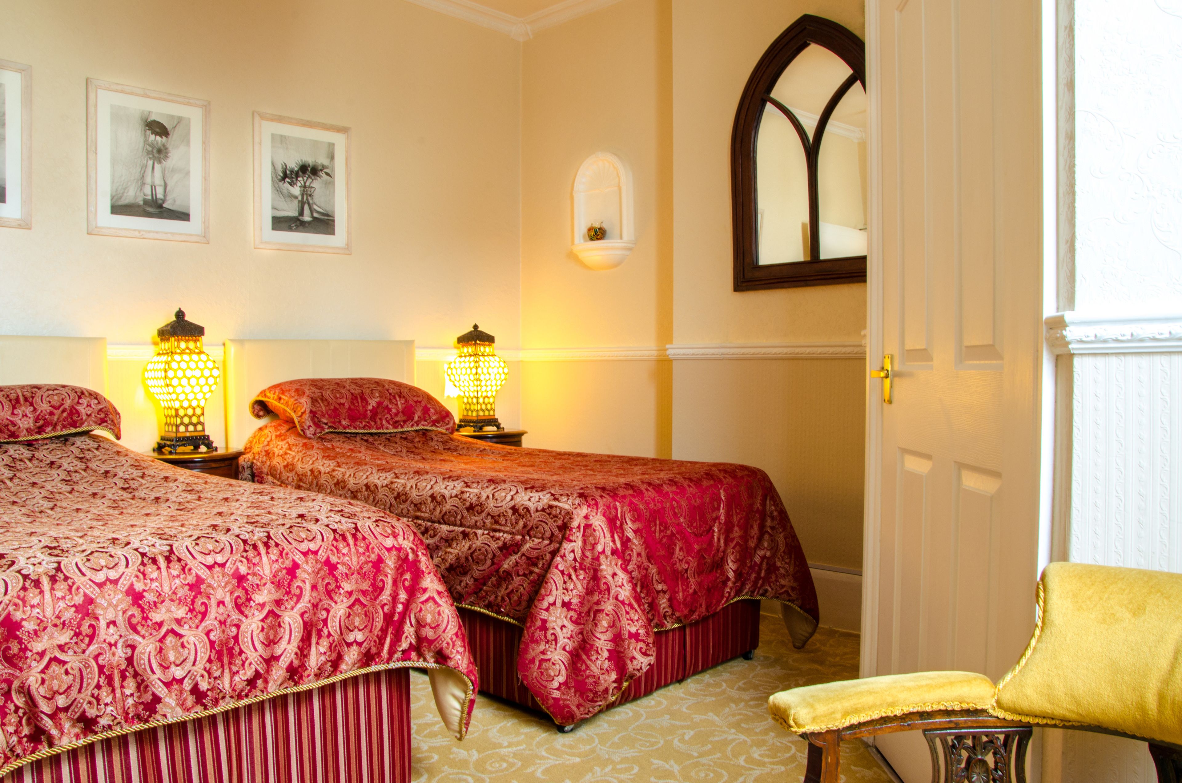 A hotel room with two beds, a chair, and a door.