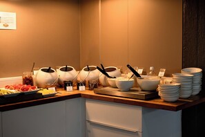 Una mesa de buffet con diversos alimentos y utensilios para servir.