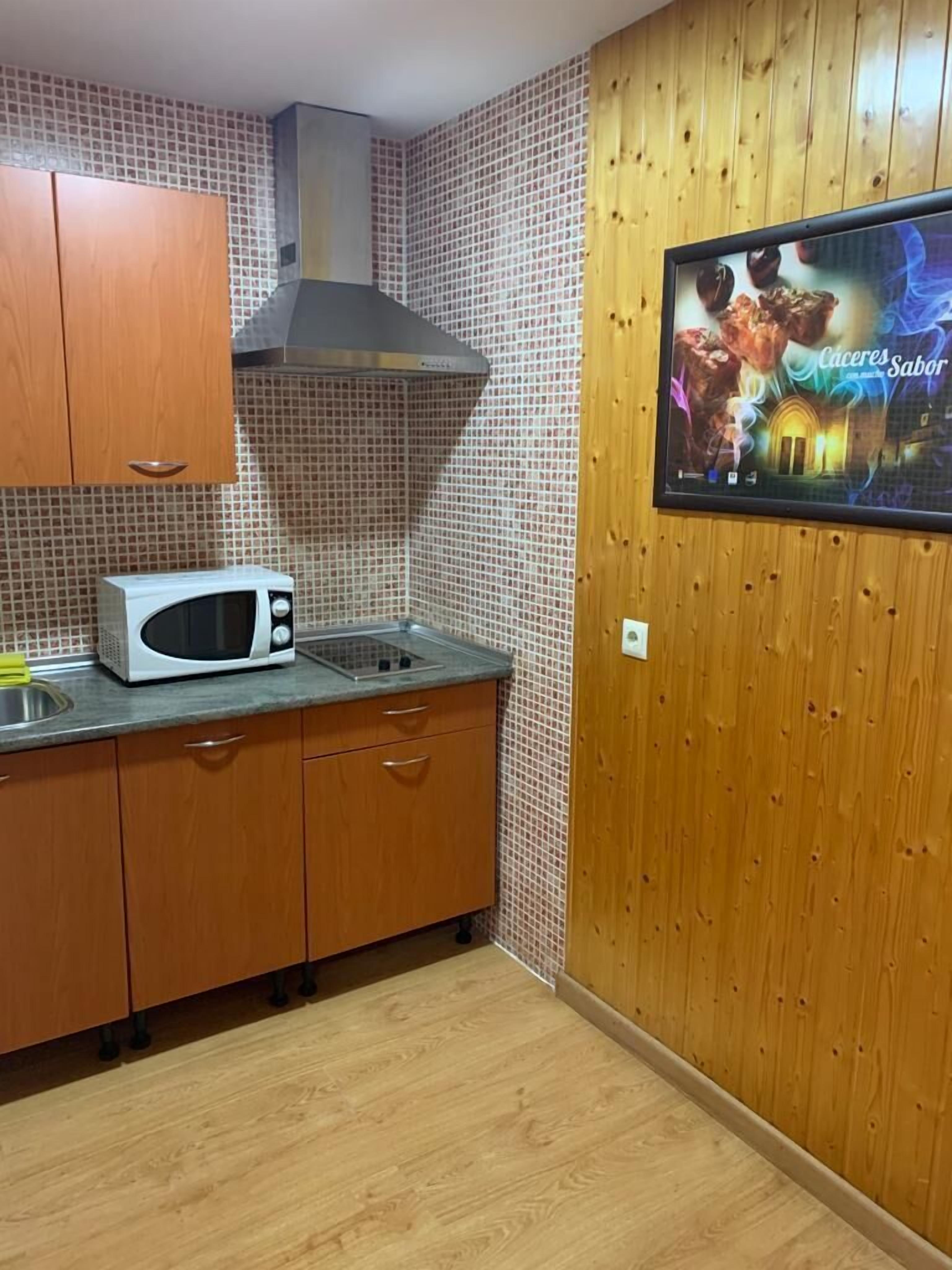 Una cocina con armarios de madera, microondas y salpicadero de azulejos.