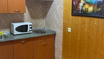 Una cocina con armarios de madera, microondas y salpicadero de azulejos.