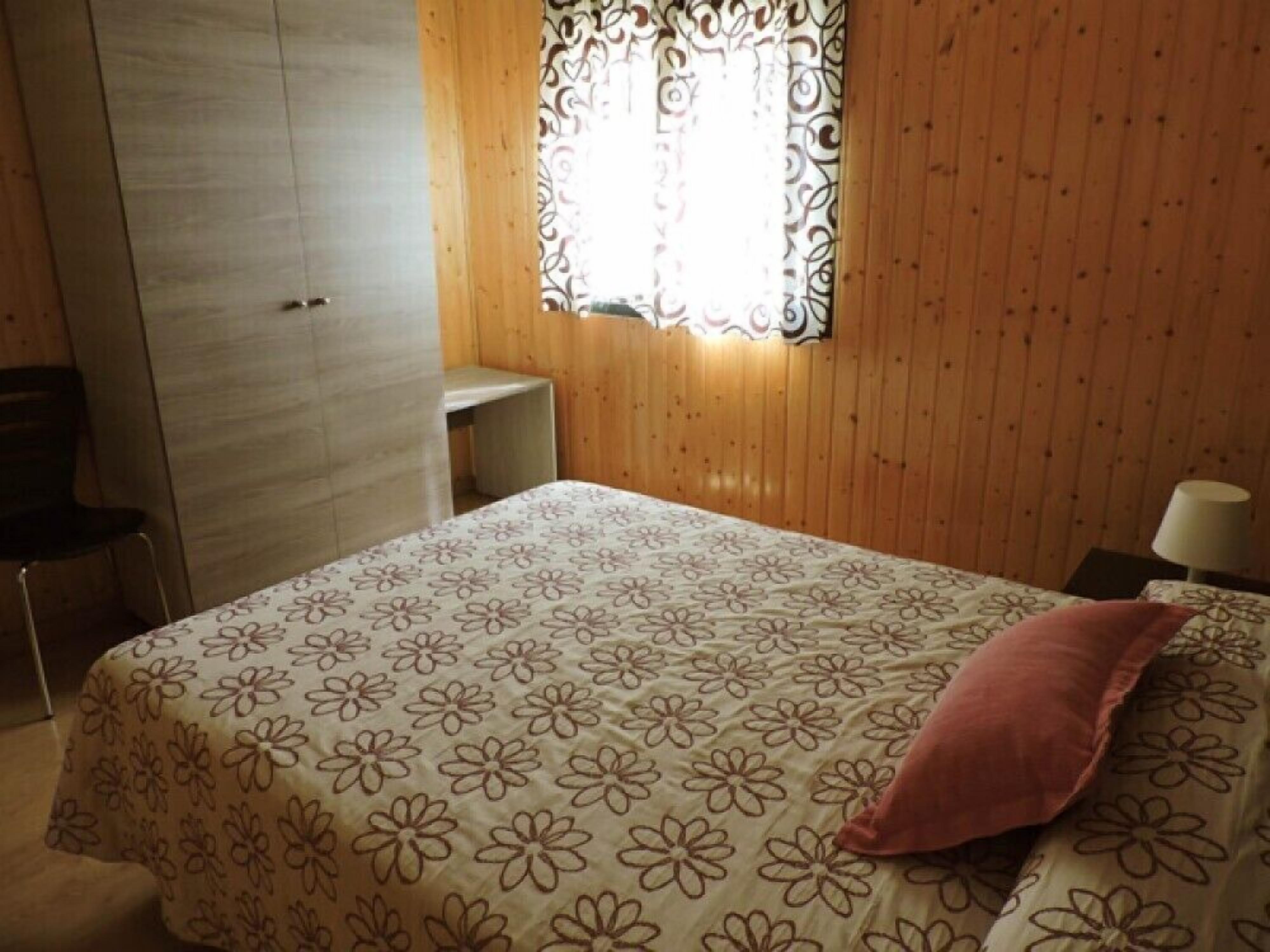 Un dormitorio con cama, escritorio y armario.