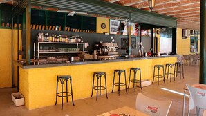 Un bar con una barra amarilla, taburetes negros y techo de ladrillo.