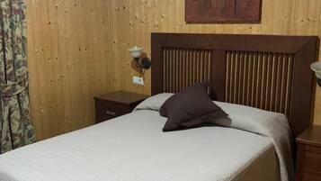 Een kamer met houten lambrisering, een bed, een nachtkastje en een kunstwerk aan de muur.