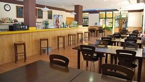 Un restaurante con mesas y sillas de madera, una barra con un tablero de menú y un reloj en la pared.