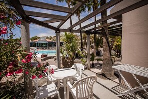 An outdoor patio area with a pool, white plastic chairs, and tables. - Caybeach Princess (San Bartolomé de Tirajana)