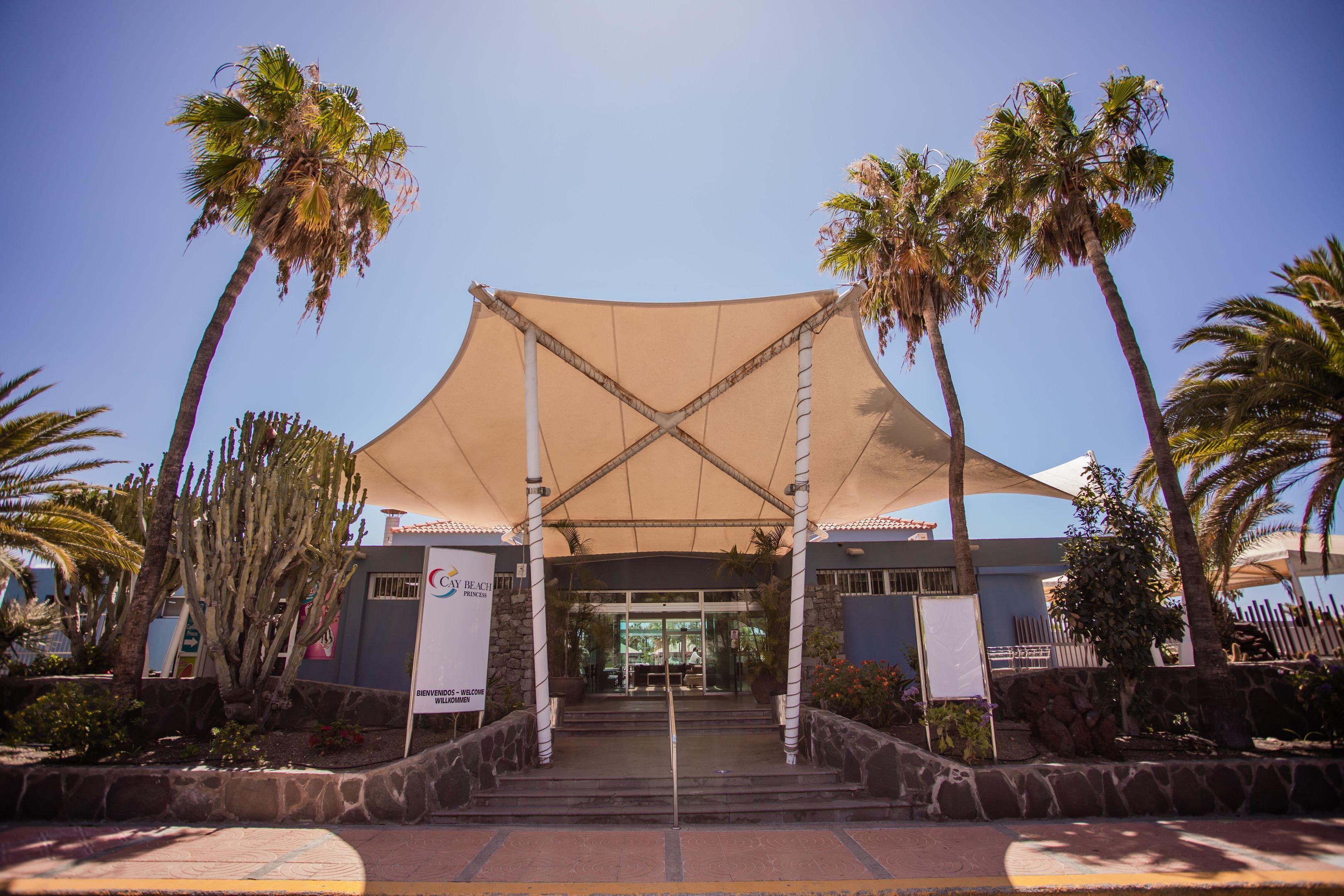 A hotel entrance with a canopy, palm trees, and a sign reading "CAY BEACH PRINCESS."