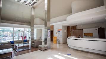 Un hall amplio con mostrador de recepción, zona de estar y ventanas grandes que dejan entrar luz natural.