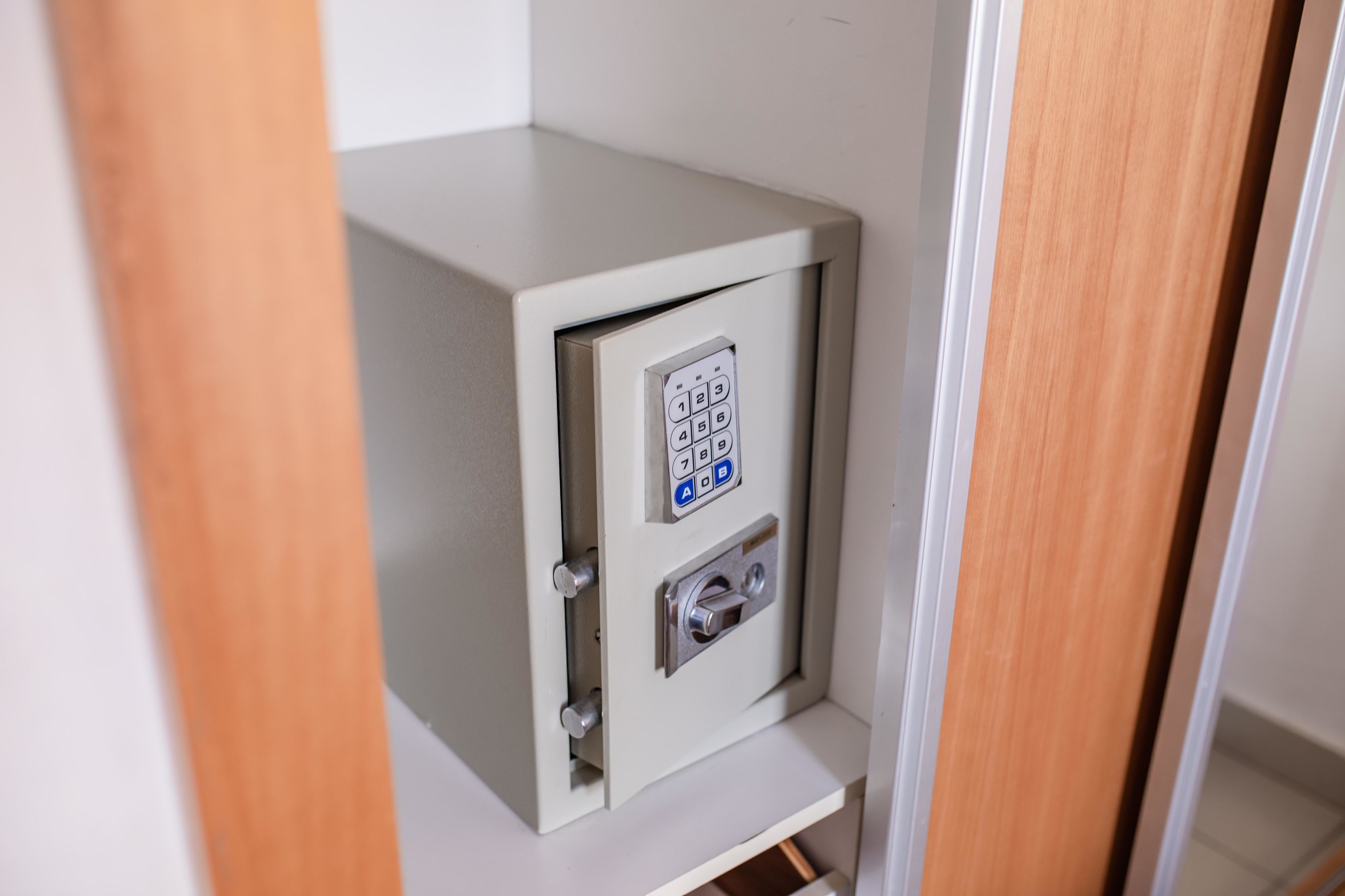 Una caja fuerte metálica y segura, con cerradura numérica, ubicada en un estrecho pasillo con puertas de madera.