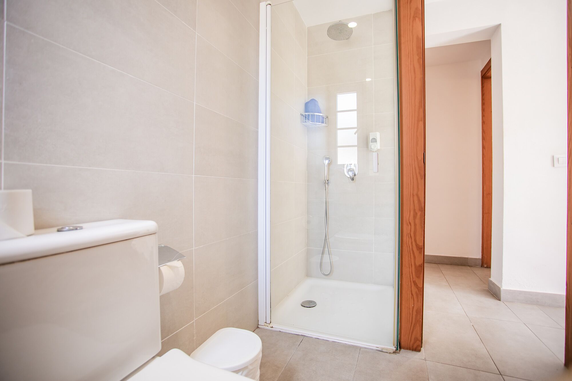 A modern bathroom with a glass-enclosed shower, a toilet, and a sink.