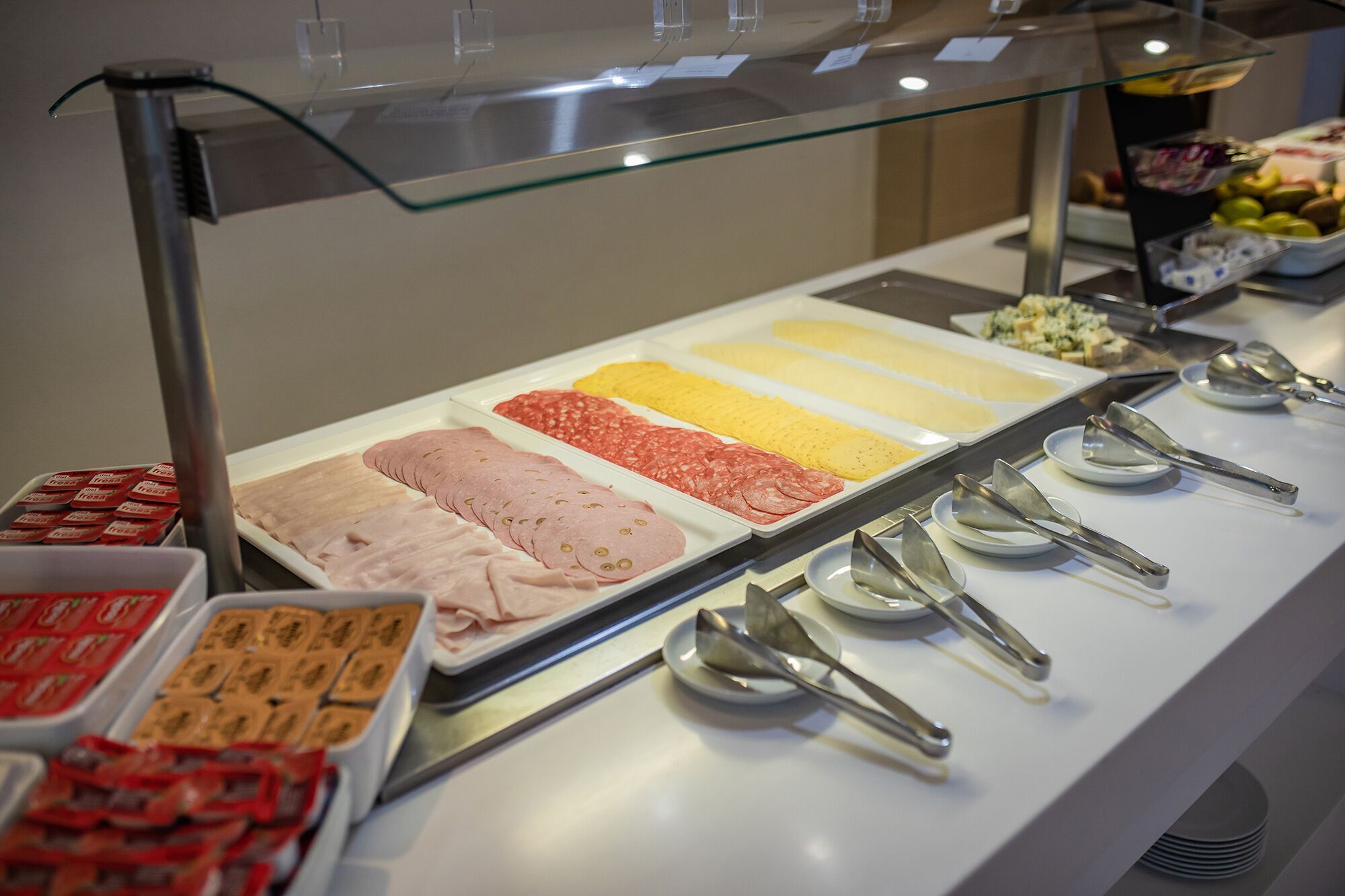 Un bufé con diversas opciones de comida, incluyendo carnes y quesos en rodajas.