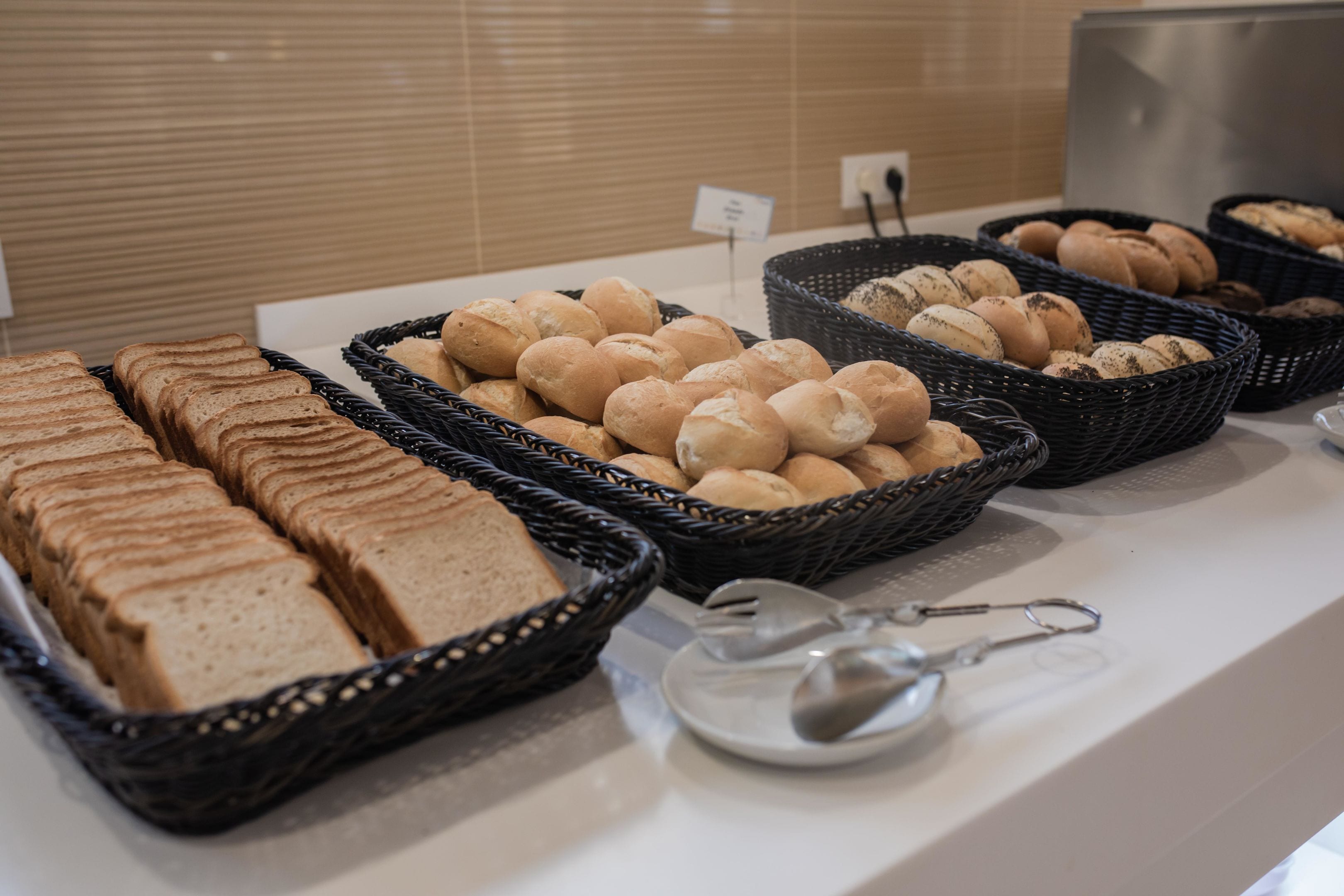 A buffet with various breads and pastries in baskets.